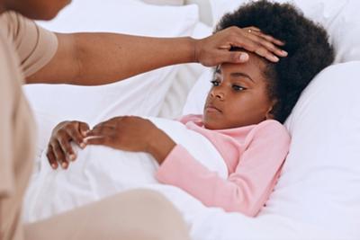 Mother assessing her child's fever by touching the forehead.