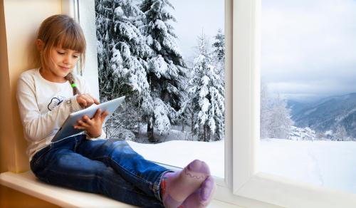 Young girl using tablet near window on cold day